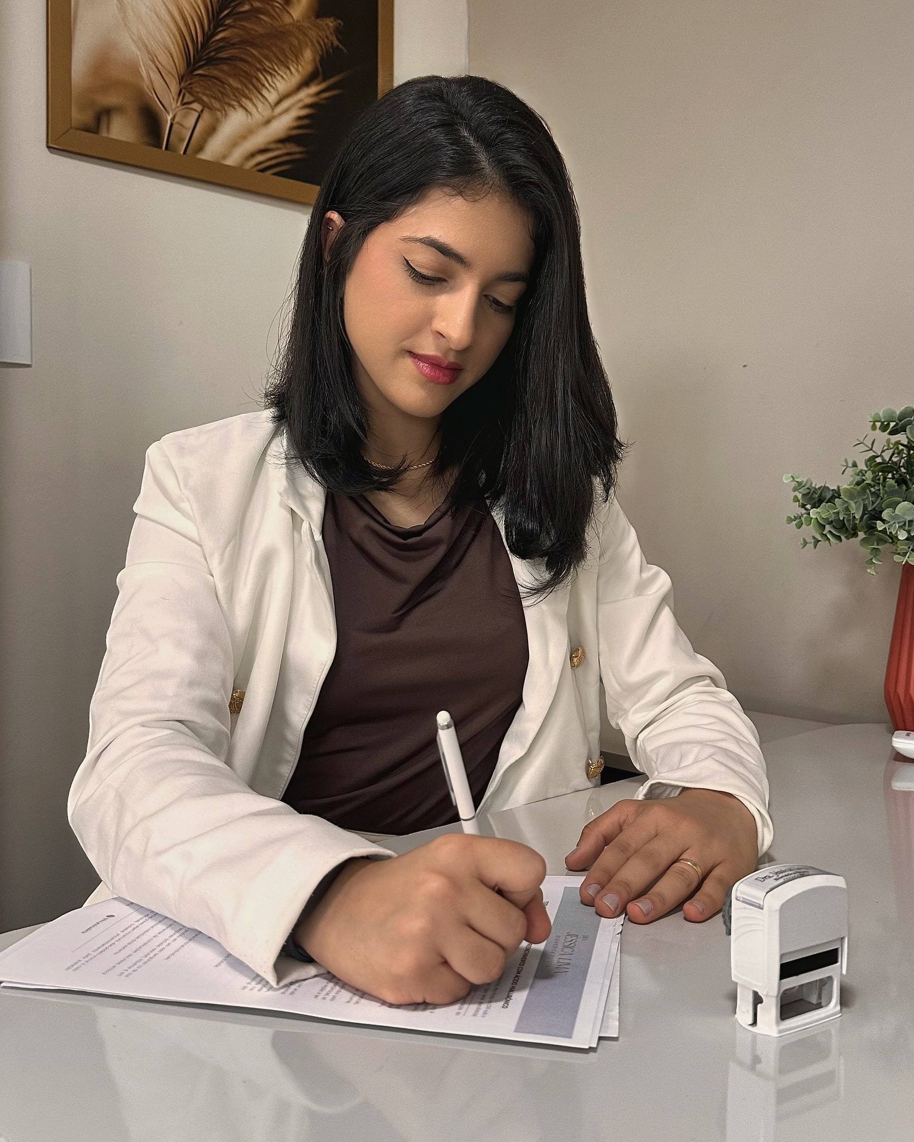 Dra. Jéssica Lima escrevendo o plano de tratamento à mesa do consultório